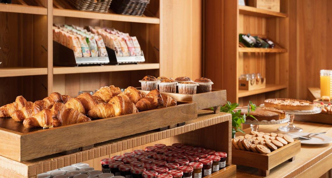 Buffet di colazione con croissant, muffin, biscotti e succhi di frutta.