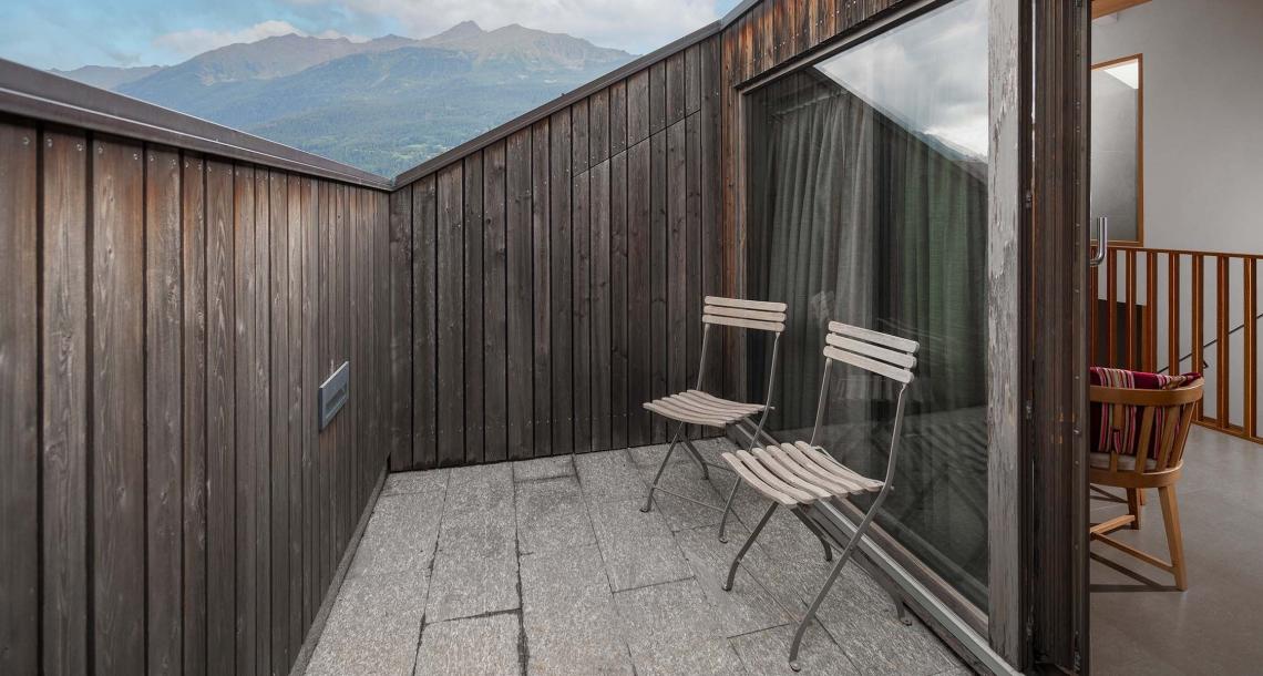 Terrazza con sedie in legno, vista montagna, design moderno e minimalista.