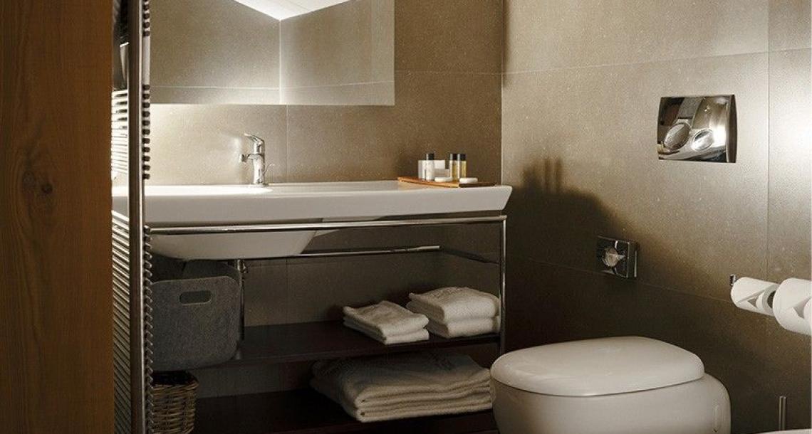 Bagno moderno con soffitto inclinato, lavabo, WC e bidet, scaffale con asciugamani.