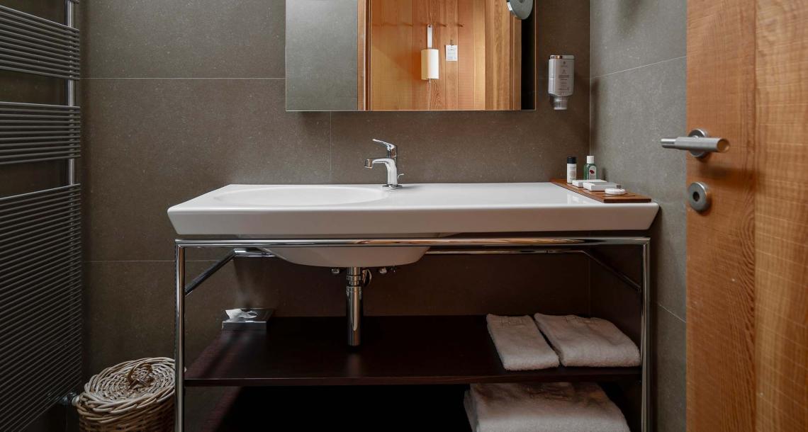 Bagno moderno con lavabo, specchio, asciugamani e accessori da toeletta.