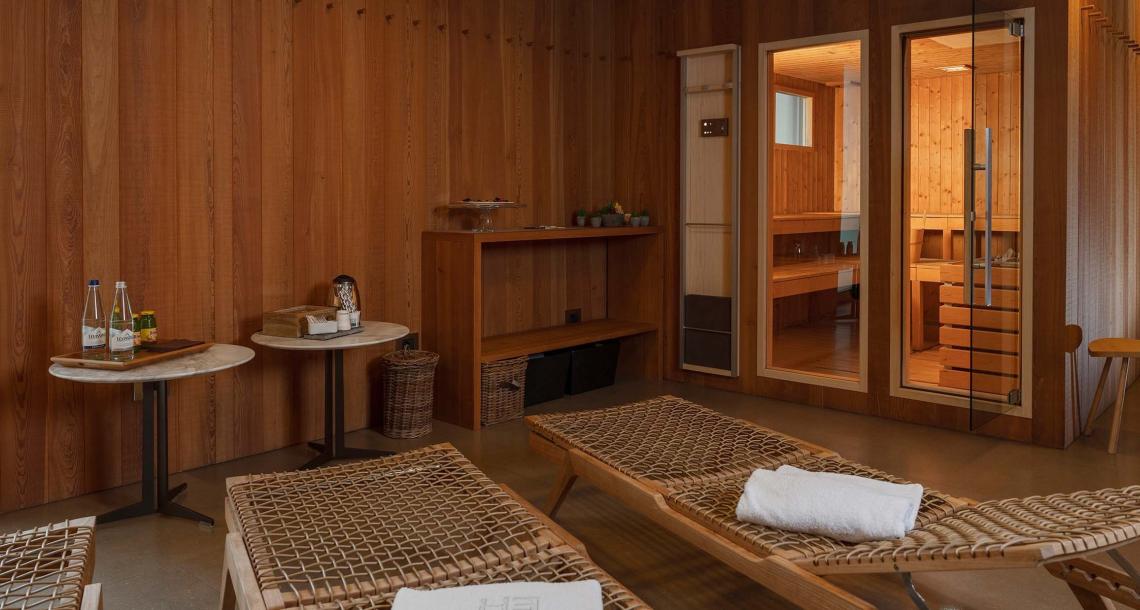 Sala relax con lettini in legno e sauna in ambiente elegante.