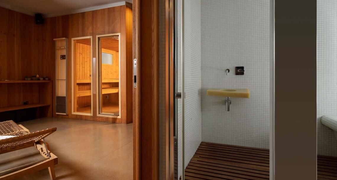 Interno di una sauna con doccia e lettino in legno.