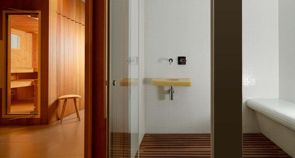 Interno moderno con sauna in legno e bagno turco, design elegante e minimalista.