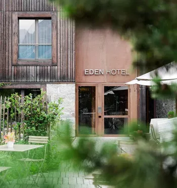 Ingresso dell'Eden Hotel con tavolini all'aperto e vegetazione circostante.