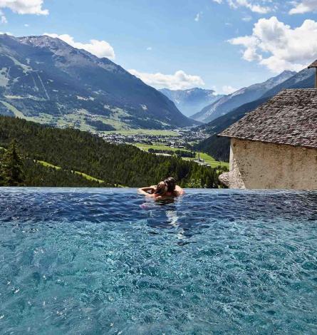 Piscina a sfioro con vista mozzafiato sulle montagne e una valle verde.